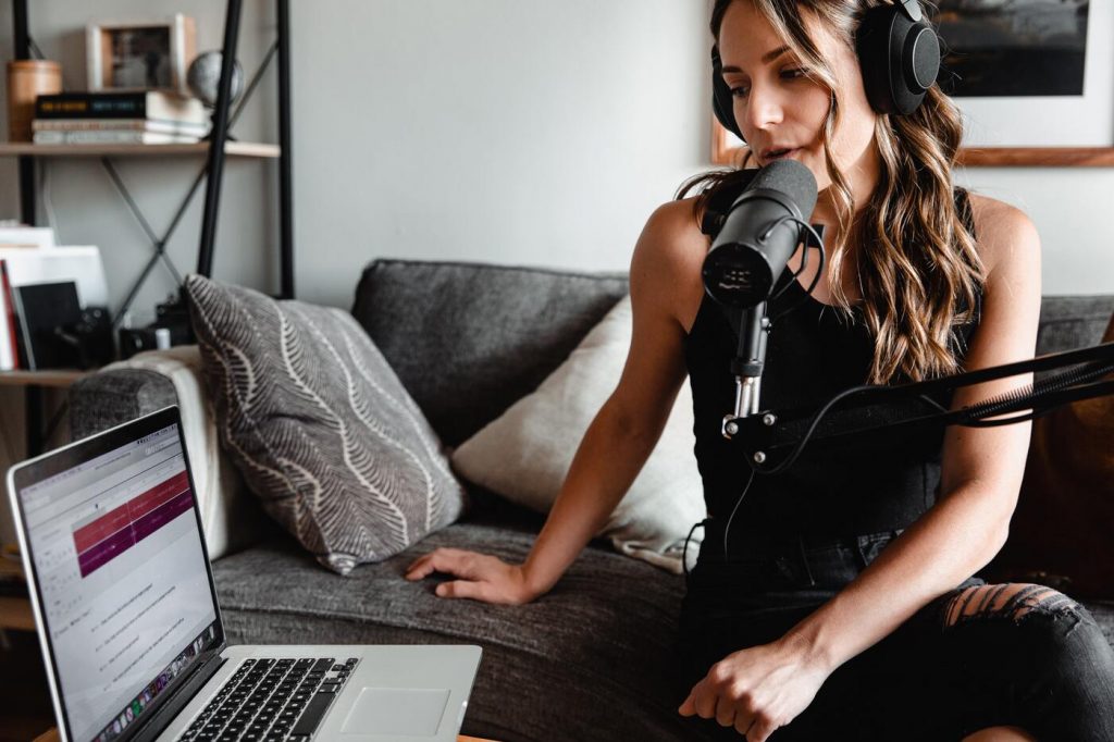 Girl podcasting with microphone and laptop on the couch