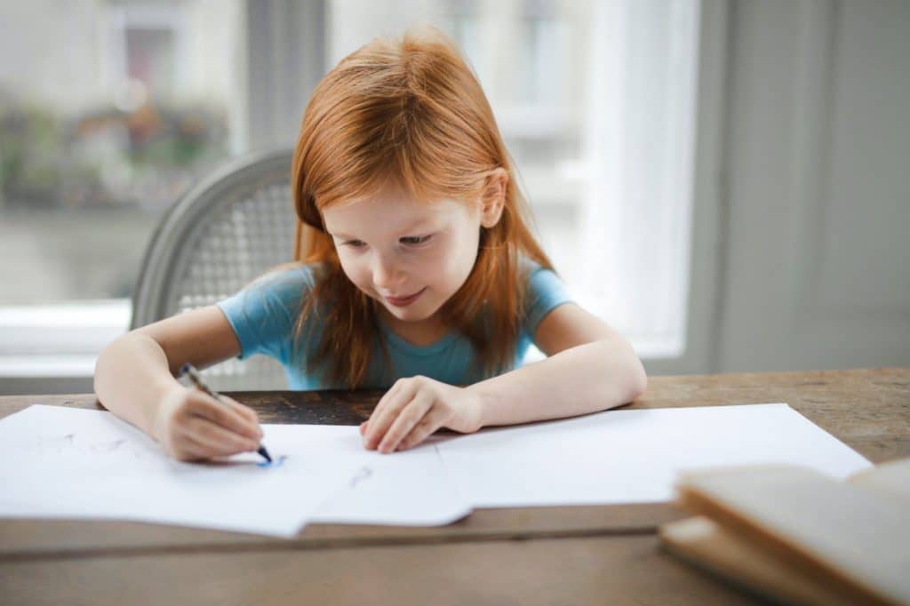 Red haired girl drawing at a desk